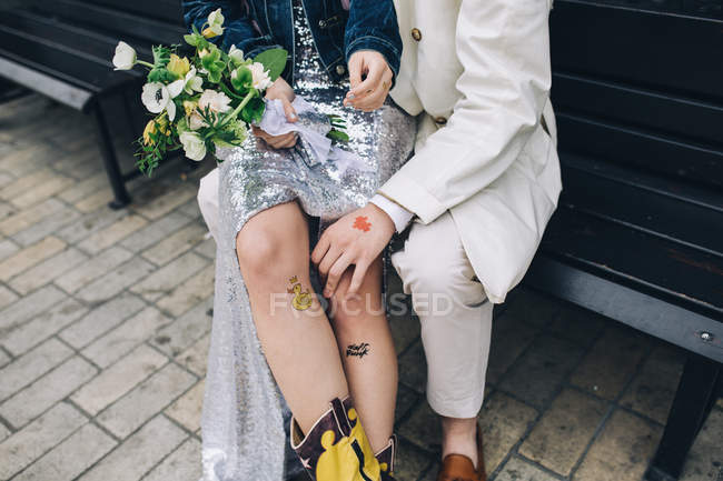 Donna appena sposata seduta sulle ginocchia dello sposo sulla panchina urbana — Foto stock