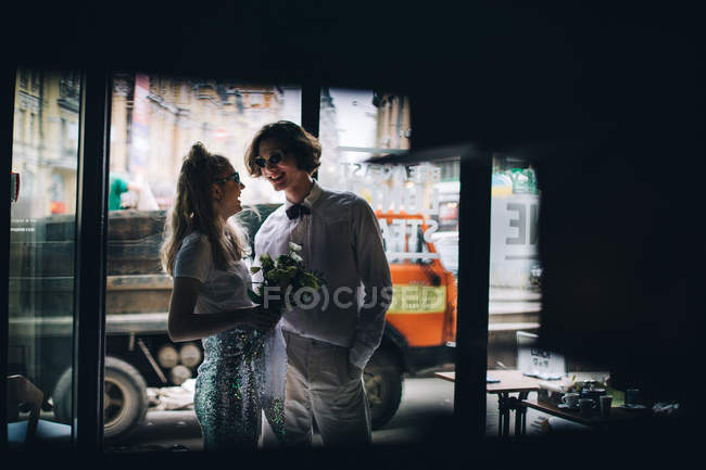 Newlywed couple with bridal bouquet and urban street in background — Stock Photo