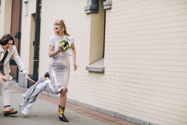 Sposi che inseguono sposa e ridono sulla strada della città — Foto stock