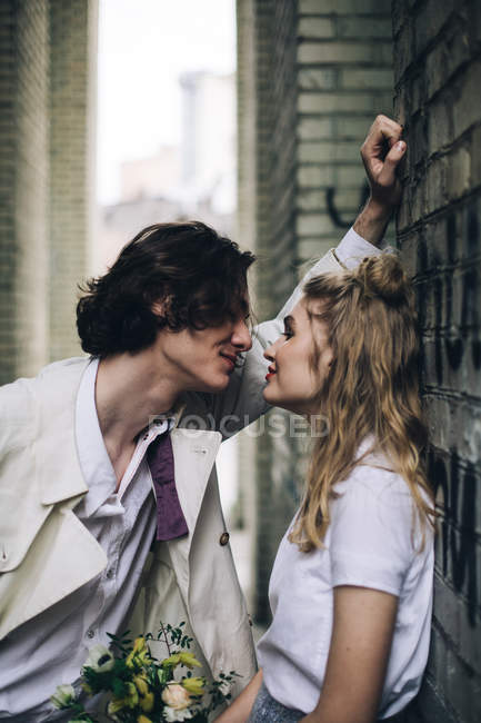 Молодая пара склоняется лицом к лицу на краю стены — стоковое фото
