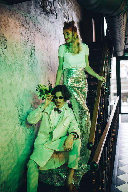 Elegante pareja recién casada posando en una escalera urbana en un edificio antiguo - foto de stock
