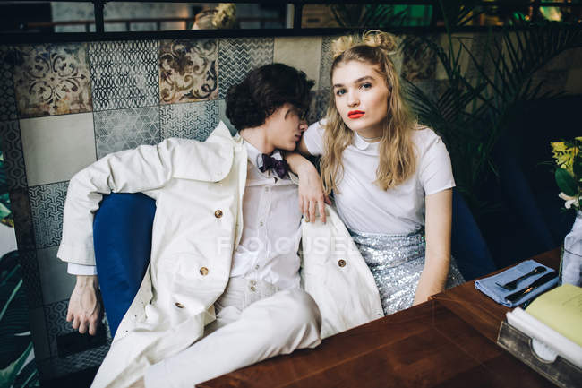 Giovane coppia alla moda seduta a tavola in interno caffè — Foto stock