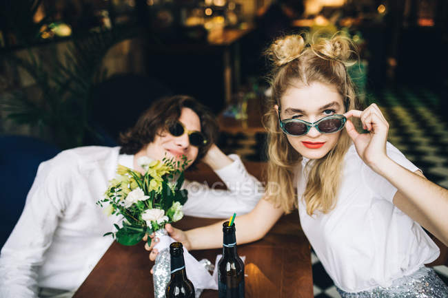 Молода пара в сонцезахисних окулярах позує в барному інтер'єрі — стокове фото