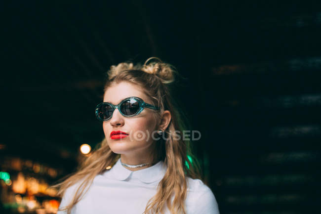 Retrato de mujer joven con estilo en gafas de sol con peinado de doble moño - foto de stock