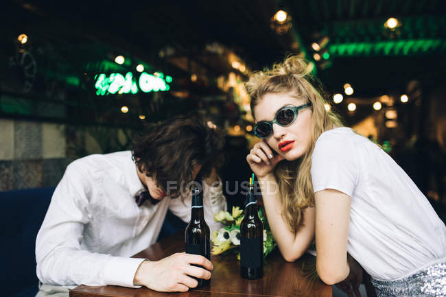 Stylish couple in sunglasses sitting in bar with beer — Stock Photo