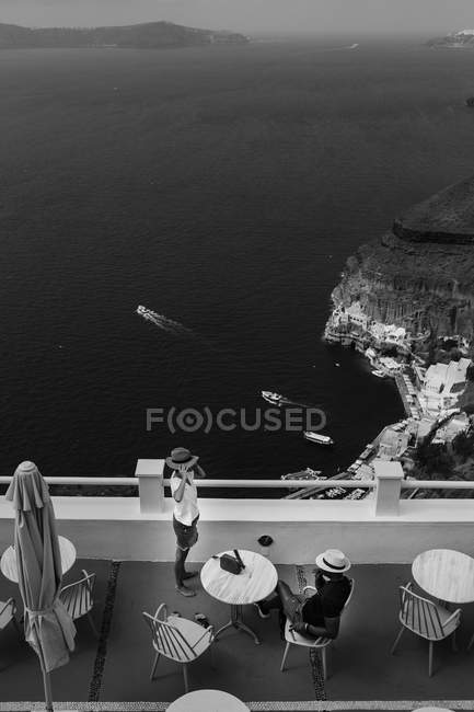 Monochrome image of hotel in majestic Santorini with relaxing travelers, South Aegean, Thira, Santorini, Greece — Stock Photo