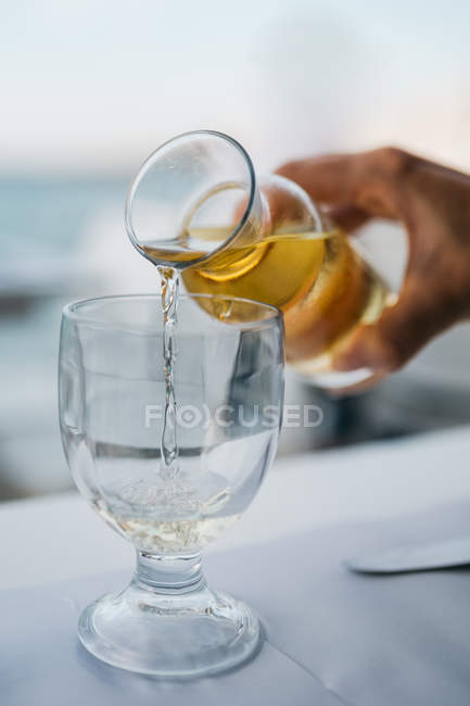 Cropped image of male hand pouring white wine in wineglass — Stock Photo