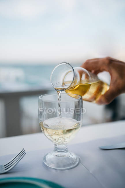 Immagine ritagliata di mano maschile versando vino bianco in bicchiere da vino — Foto stock