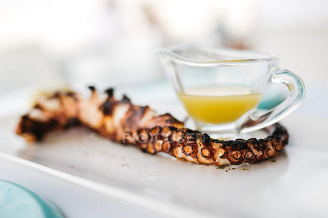 Closeup view of octopus tentacle with sauce in restaurant — Stock Photo
