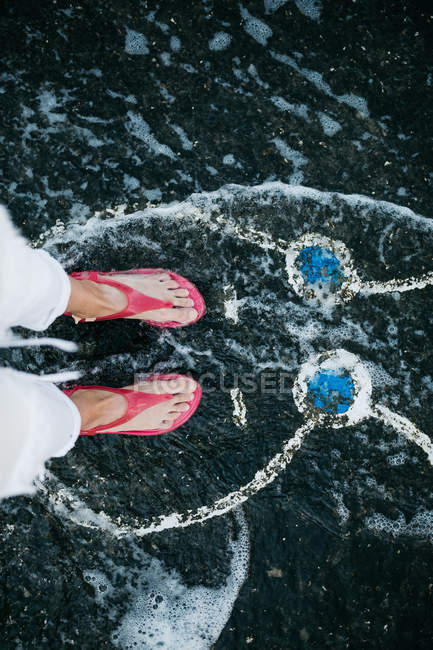 Cropped image of female feet standing on black beach with rabbit picture — Stock Photo
