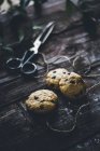 Baked chocolate chip cookies on wooden surface with twine and scissors — Stock Photo