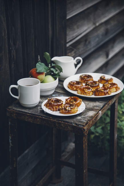 Запечені яблучні пончики з карамеллю на тарілках на сільському табуреті — стокове фото