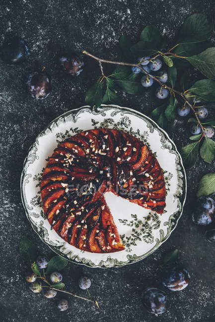 Gewürzpflaumenkuchen mit Brandy auf grauer Oberfläche mit frischen Pflaumen — Stockfoto