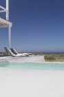 Liegestühle gegen Pool in luxuriösem modernen Haus — Stockfoto