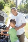 Portrait of smiling grandfather working on car engine with grandson — Stock Photo