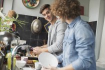 Young men roommates cooking and doing dishes in kitchen — Stock Photo
