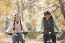 Улыбающиеся мать и дочь езда на велосипеде на открытом воздухе — стоковое фото