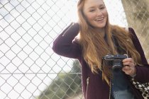 Щаслива молода жінка тримає камеру на відкритому повітрі — стокове фото