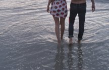 Jovem casal caminhando no oceano surf — Fotografia de Stock