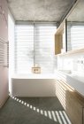 Lumière à travers les stores derrière la baignoire trempée dans la salle de bain moderne — Photo de stock