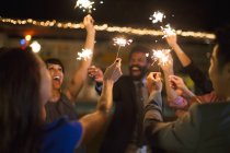 Friends playing with sparklers at party — Stock Photo