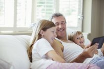 Padre e figli che usano tablet digitale sul letto — Foto stock
