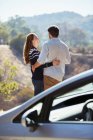 Casal feliz abraçando na estrada do lado de fora do carro — Fotografia de Stock