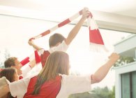 Family in sports jerseys cheering in living room — Stock Photo