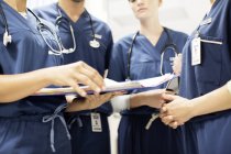 Ärzteteam mit Stethoskopen schaut sich Dokumente im Krankenhaus an — Stockfoto