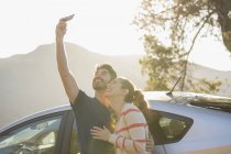 Couple heureux prenant auto-portrait avec téléphone caméra voiture extérieure — Photo de stock
