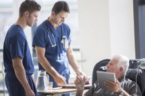 Пацієнт використовує планшетний ПК і розмовляє з лікарями в лікарні — стокове фото