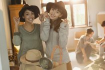 Portrait young women friends trying on hats moving into apartment — Stock Photo