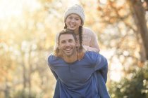 Portrait enthusiastic father piggybacking daughter outdoors — Stock Photo