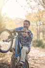 Father teaching son how to do a wheelie in woods — Stock Photo