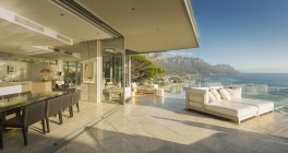 Солнечный современный роскошный внутренний дворик с видом на океан и горы — стоковое фото