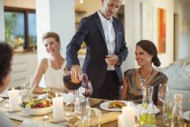 Mann schenkt Wein bei Dinnerparty ein — Stockfoto