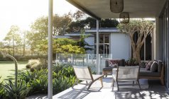 Terrasse ensoleillée avec chaises contre les plantes — Photo de stock