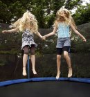 Девушки прыгают на батуте на открытом воздухе — стоковое фото