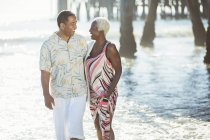Seniorenpaar spaziert am sonnigen Strand — Stockfoto
