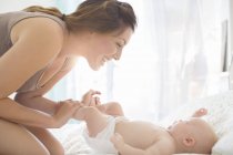 Mother playing with baby girl on bed — Stock Photo