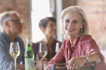 Портрет улыбающейся пожилой женщины, обедающей с друзьями в ресторане — стоковое фото