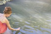 Mujer sumergiendo su mano en la piscina - foto de stock