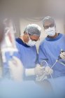 Médicos maduros realizando cirurgia e controlando líquido em saco salino — Fotografia de Stock