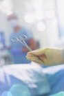 Cirurgião usando luva de borracha segurando tesoura cirúrgica na sala de cirurgia — Fotografia de Stock