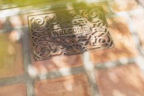 Sun shining through tree branches on welcome mat — Stock Photo