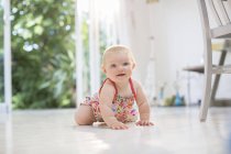 Baby girl crawling on kitchen floor — Stock Photo