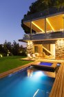Casa moderna con vistas a la piscina iluminada por la noche - foto de stock