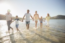Família caminhando em águas rasas na praia — Fotografia de Stock