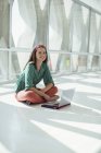 Портрет уверенной деловой женщины с ноутбуком на полу в солнечном офисе — стоковое фото