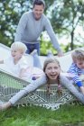 Padre empujando a los niños en hamaca al aire libre - foto de stock